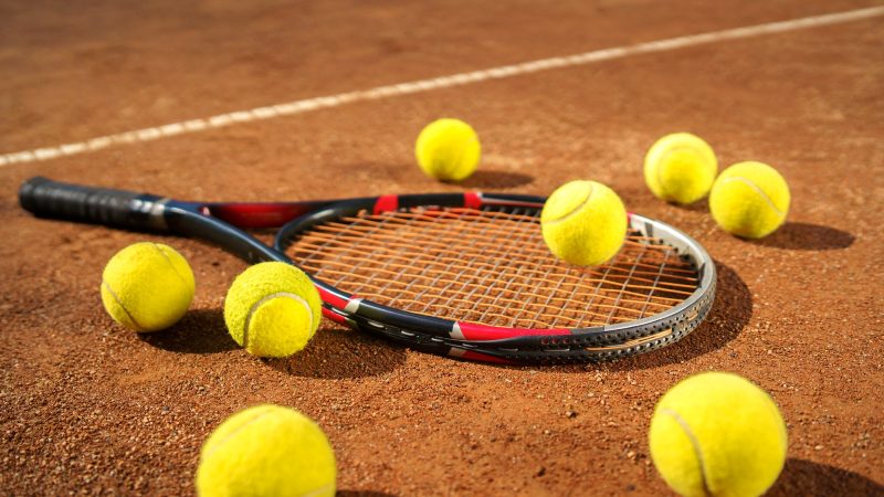 Racket and scattered tennis balls on the court
